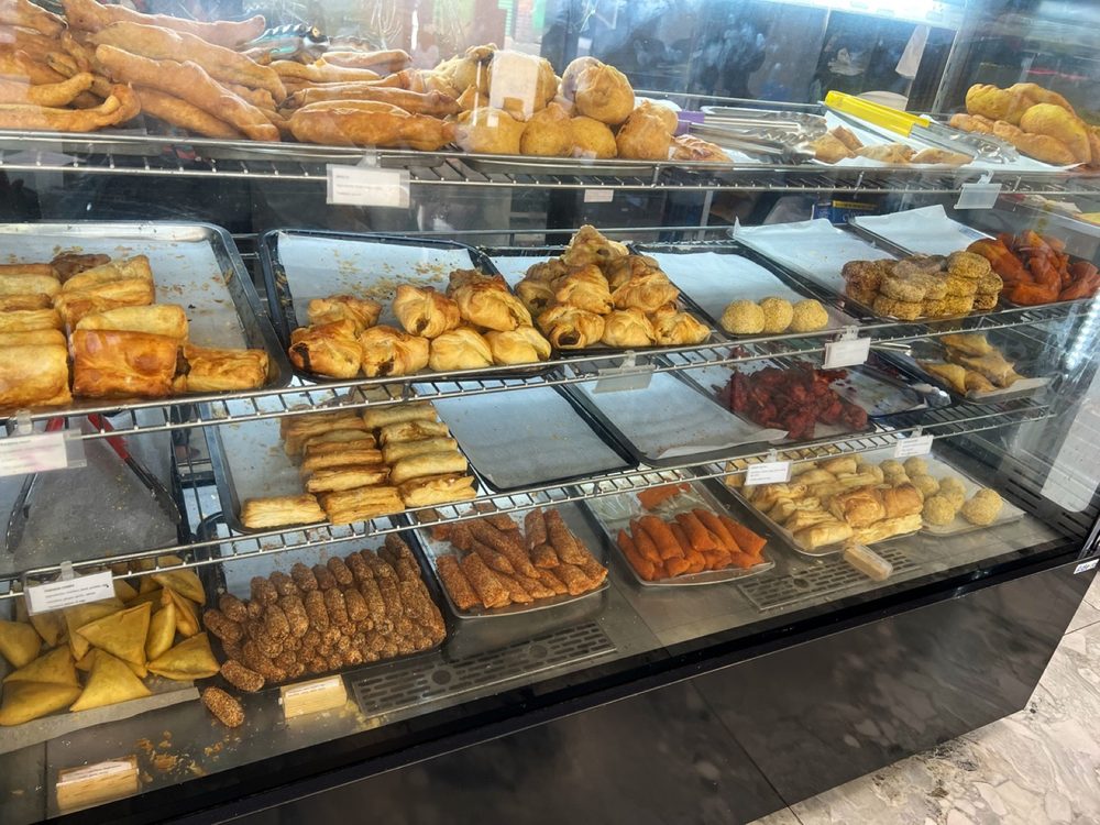 The glass display counter packed with trays of samosas, puffs and cutlets