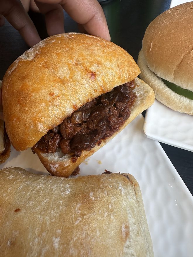 Close crop of a spiced meat ciabatta roll held in one hand