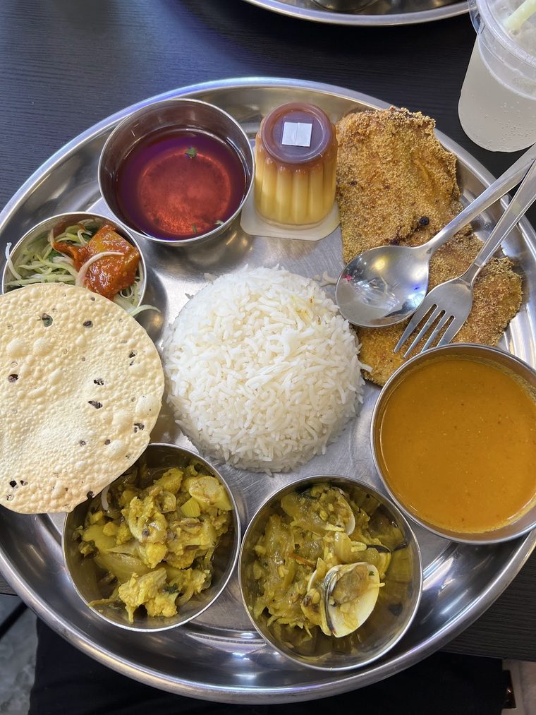A steel thali of rice, curries and fried fish